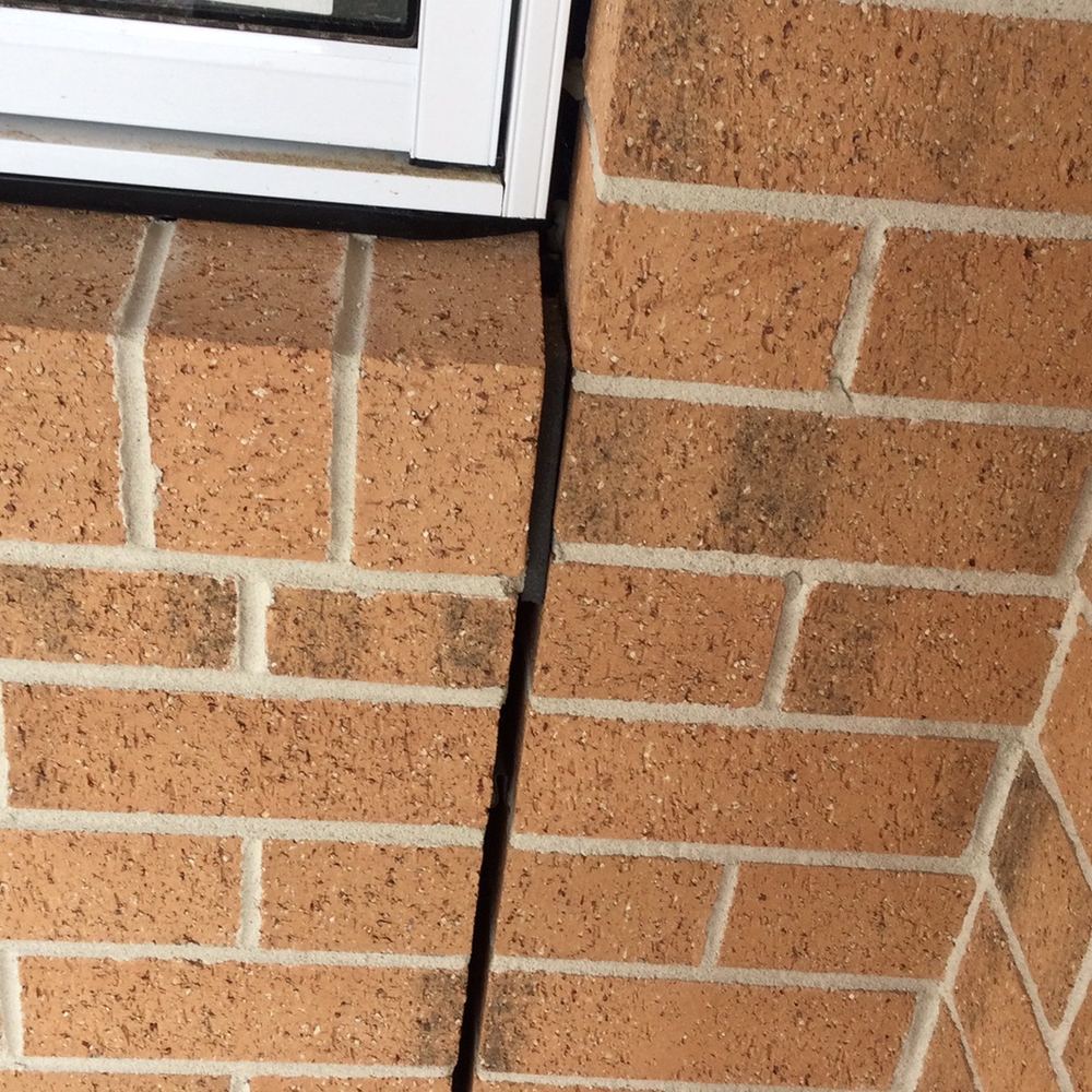 Brick expansion joint left unsealed with mortar still inside, found during a fixing inspection in Sunbury