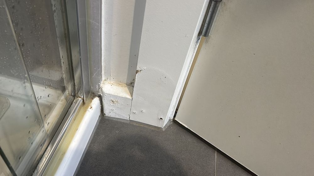 Floor swollen and deformed beside the only shower, a sign of long-term leaking, found during a defect investigation in Epping